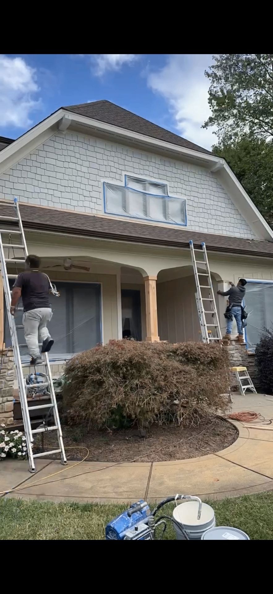 Crew on ladders masking windows and painting the front of a Lake Norman home