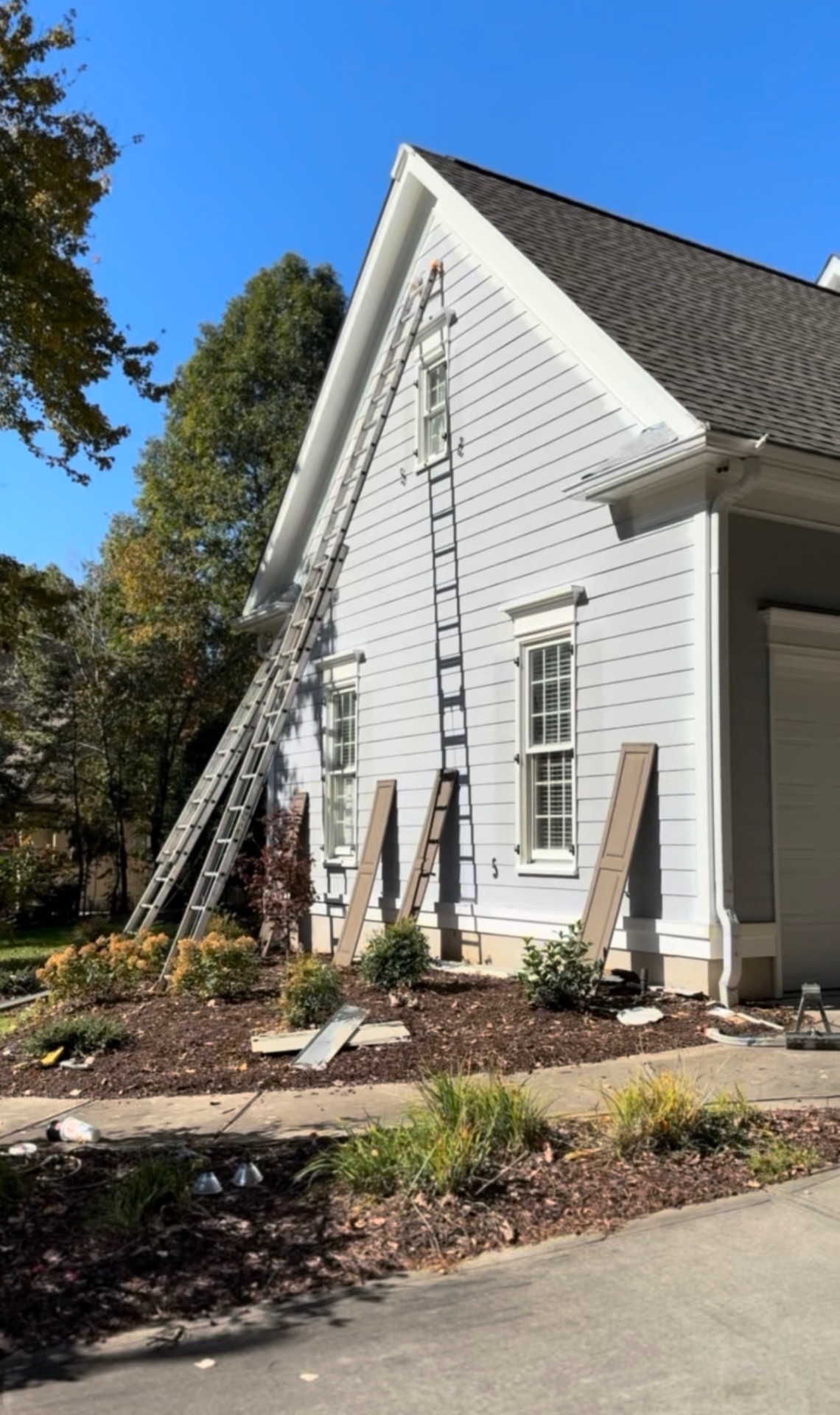 Side of the Mooresville home mid-repaint with ladders and shutters leaning against the siding